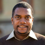 Antoine Haywood head shot in a brown sweater and white shirt.