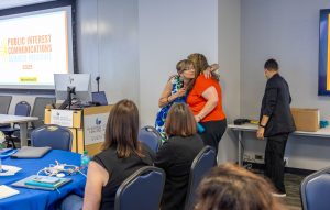 Institute director Angela Bradbery hugs Erin Hart during the closing session, which recognized attendees who helped organize the institute. Photo credit: Jenna Ayoub.