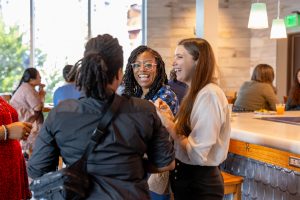 Kelsy Adams, Luna Pittet Gonzalez share a laugh with Tracy Kyles (back to camera) at the summer institute welcome reception. Photo credit: Jenna Ayoub.