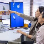 Yuan Sun points at a photo of coffee beans on this study's mocked-up website while Yang Feng looks on.
