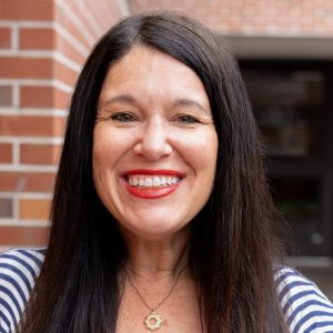 Erika Cooper Head Shot in Weimer Hall Brick Wall Atrium