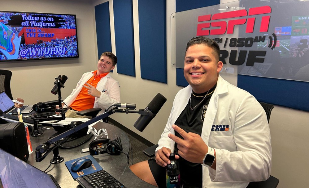 Luis Rodriguez holds up a peace sign in front of a microphone and switchboard.