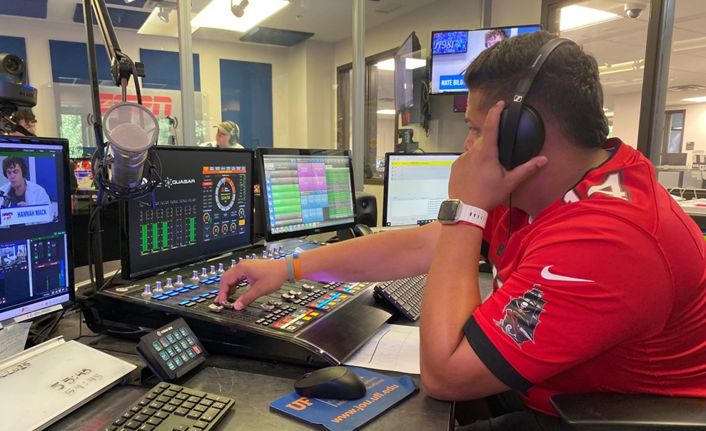Luis Rodriguez turns a knob on a large switchboard while observing the changes on a monitor in front of him.
