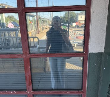 Yasmeen Hughes reflected in the glass at the train station.