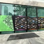 New York Film Festival sign on a glass wall above a sidewalk.