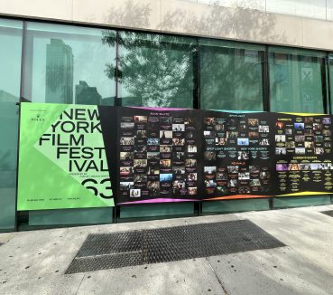 New York Film Festival sign on a glass wall above a sidewalk.