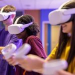 Three people wearing virtual reality headsets and holding virtual reality controllers.