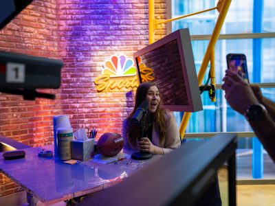 Hannah Darroch, MAMC ‘23, sits behind the mic at NBC Sports.