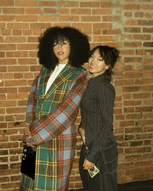 A pair of women standing in front of a red brick wall.